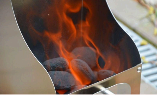Ein Anzündkamin für das einfache Entzünden von Grillkohle und Briketts. Im Anzündkamin befinden sich brennende Holzkohlebriketts